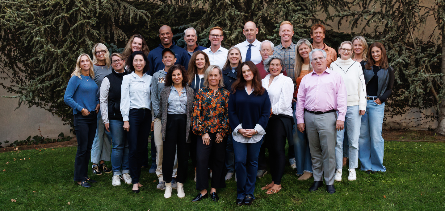 A large group of about 30 board members smiles, standing in the grass